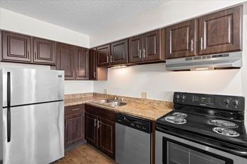 A kitchen with a stove, refrigerator, and cabinets. at Malvern Hill Apartment Homes, Kansas, 66214